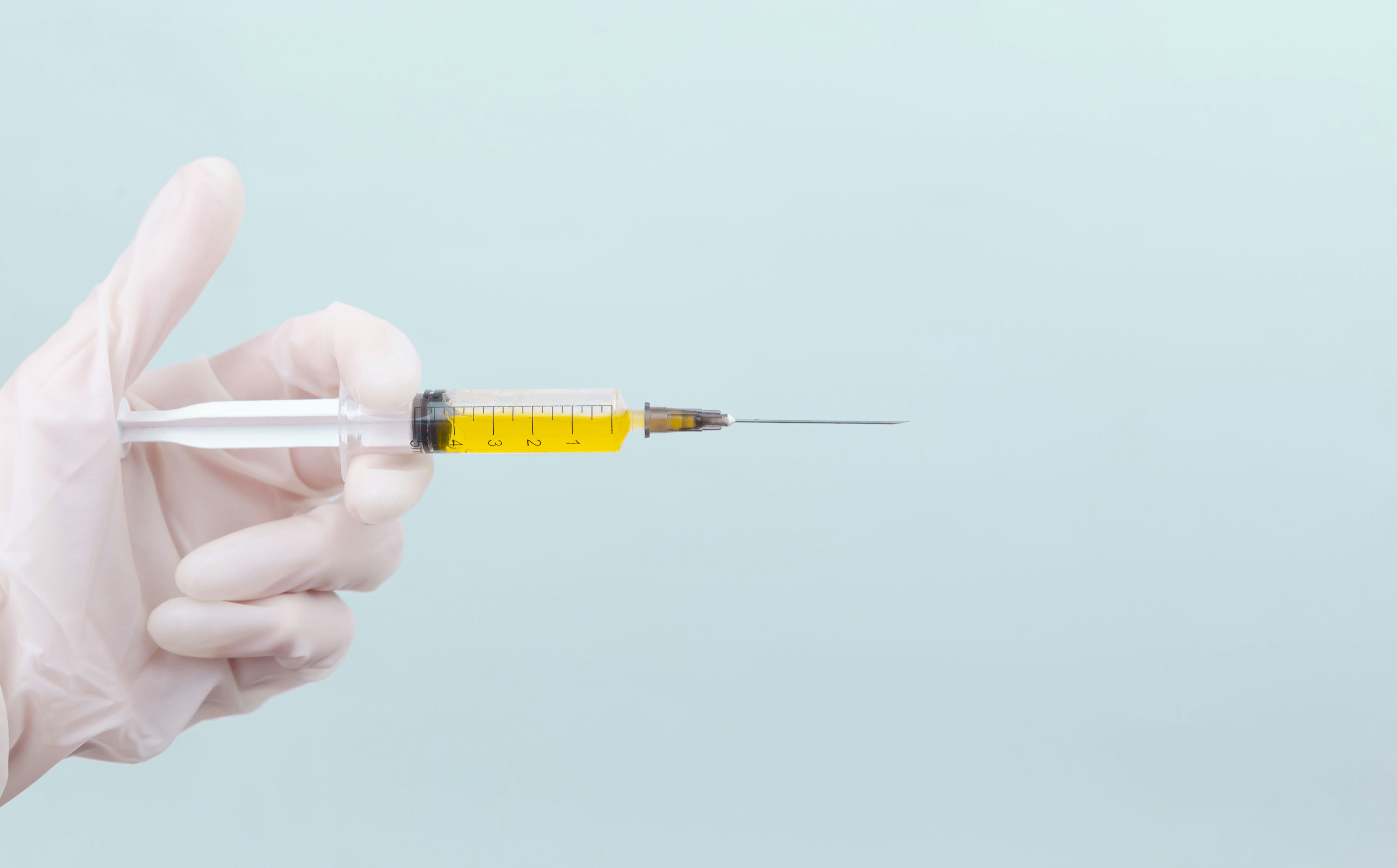 A gloved hand holding a syringe.